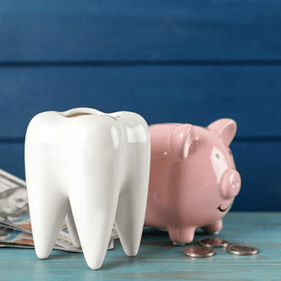 Model tooth in front of a piggy bank and money