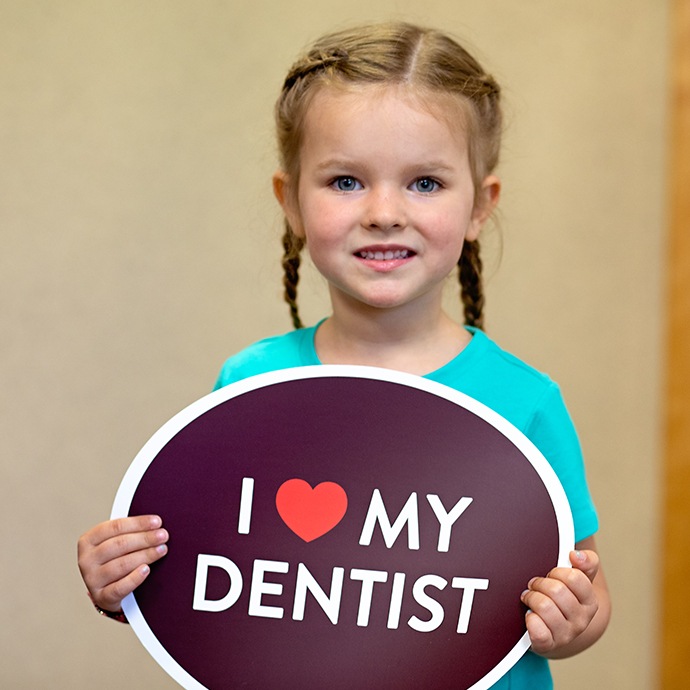Young girl in dental office holding an I love my dentist sign