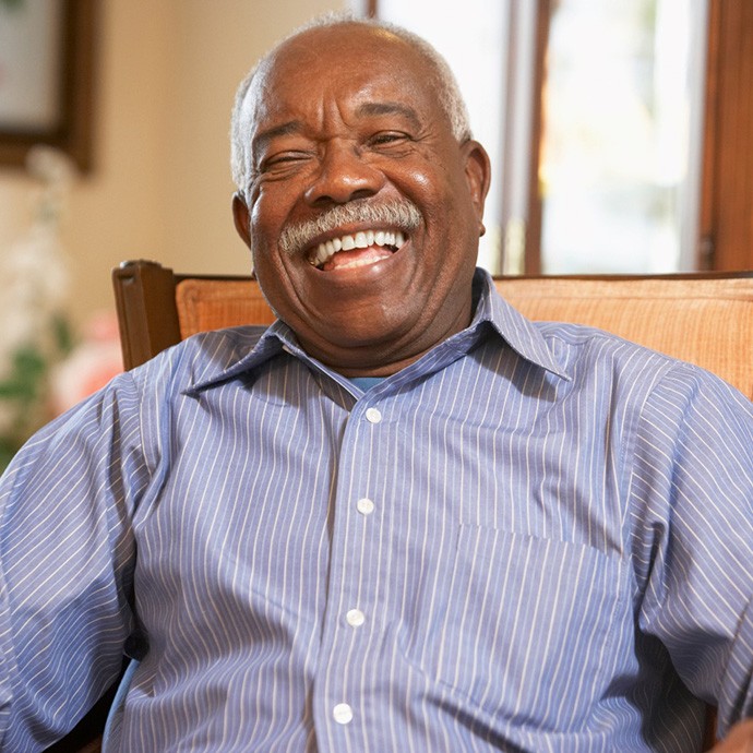 Senior man with glasses smiling with arms folded