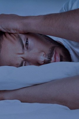 Frustrated man lying awake on his pillow because he can’t sleep