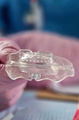 Close up of dentist holding an oral appliance next to a dental model