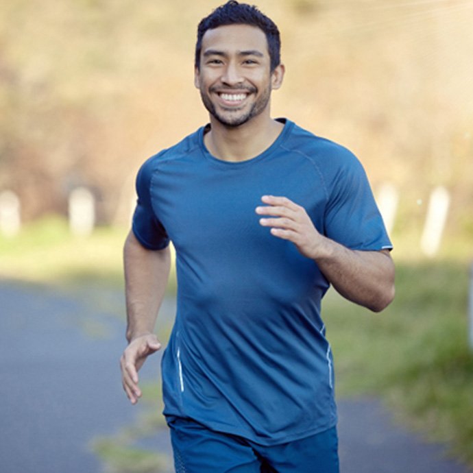 Man in blue shirt smiling and jogging down road