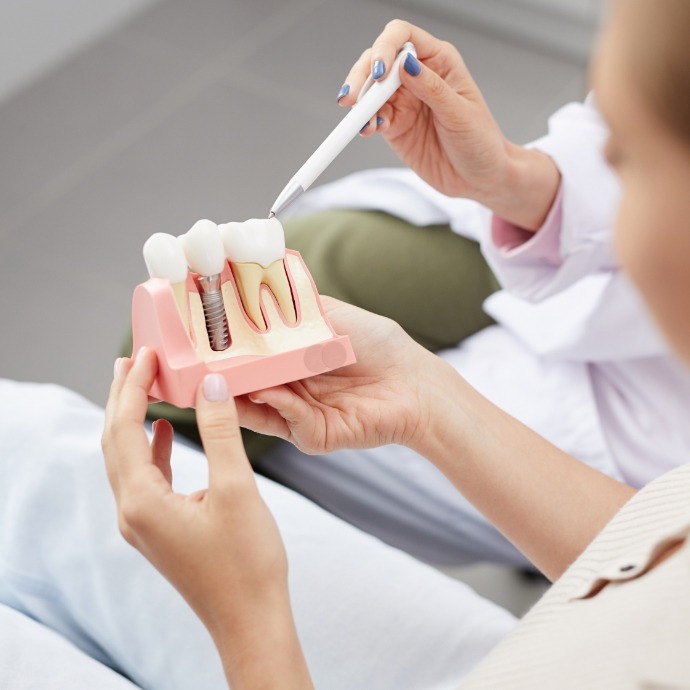 Dentist and patient looking at dental implant model
