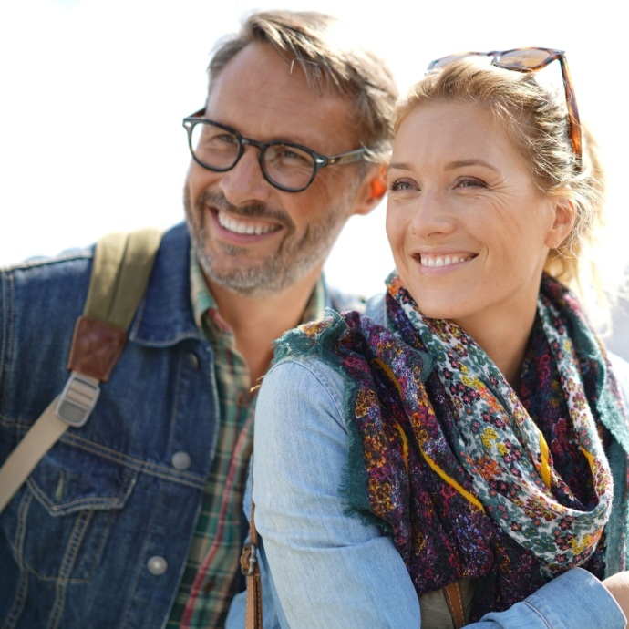 Man and woman smiling after dental implant tooth replacement