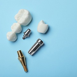 A dental bridge and dental implant materials against a blue background