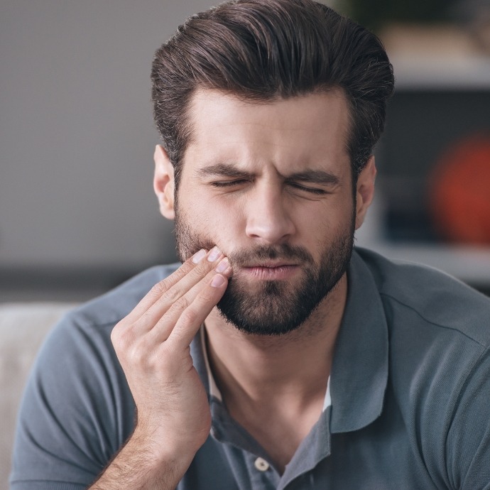 Man in need of emergency dentistry holding jaw in pain