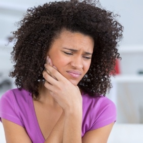 Woman with toothache holding cheek in pain