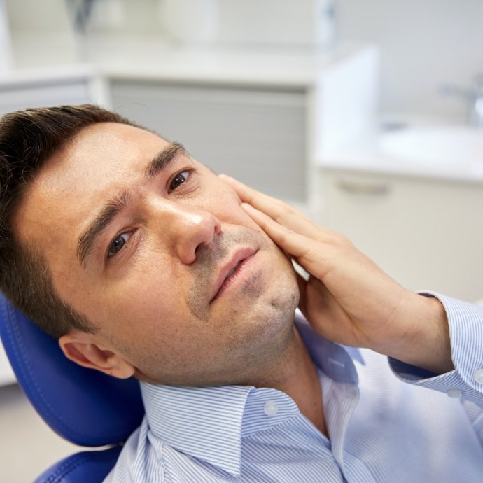 Man in need of emergency dentistry holding cheek