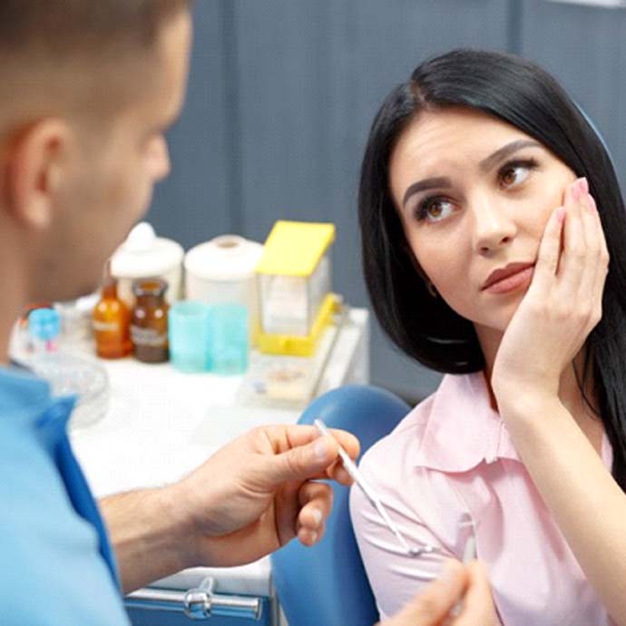 woman with tooth pain talking to emergency dentist in Longmont