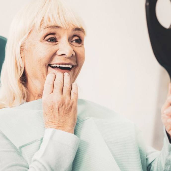 Woman admiring her new implant dentures in Longmont