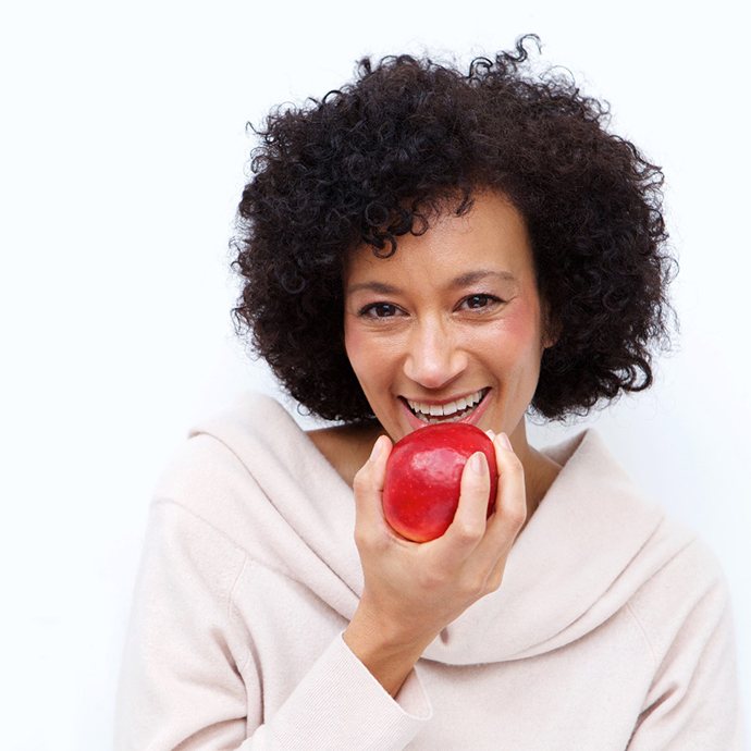 Patient with implant dentures eating an apple