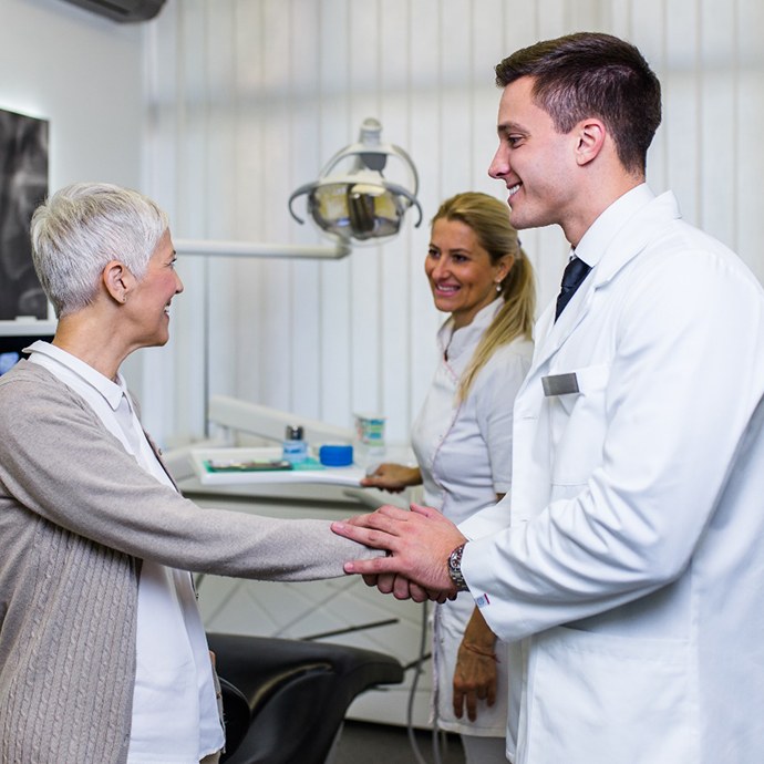 a patient shaking hands with their implant dentist in Longmont