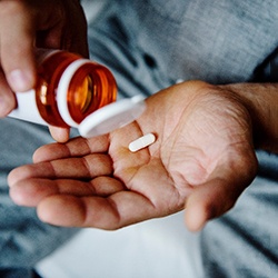 a person taking pills for dental implant post-op instructions