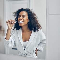a woman carefully brushing her teeth and dental implants