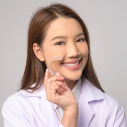 Woman smiling while holding Invisalign aligner