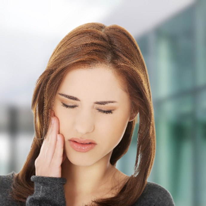 Close-up of a woman rubbing her jaw due to discomfort