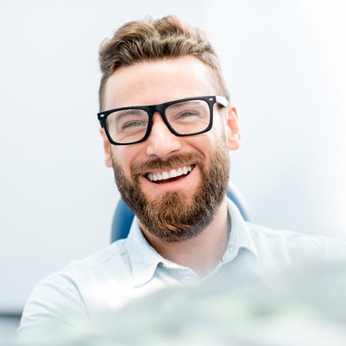 man smiling while sitting in dental chair 