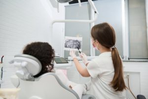 dentist showing jaw and teeth with X-ray during consultation