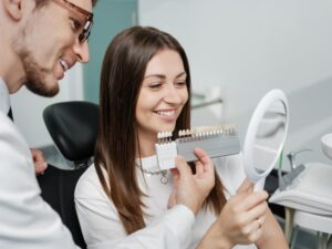 Dentist holding up veneers to patient.
