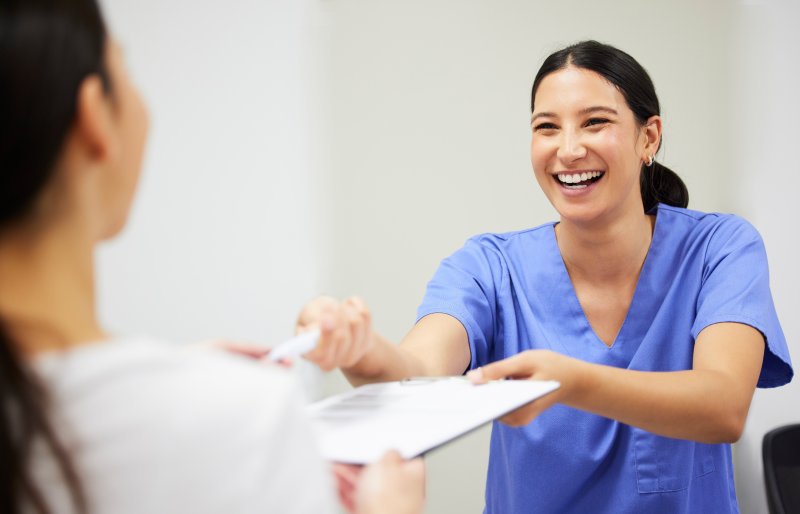 A nurse handing dental insurance forms to a patient