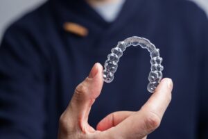 Dentist holding Invisalign clear aligner.